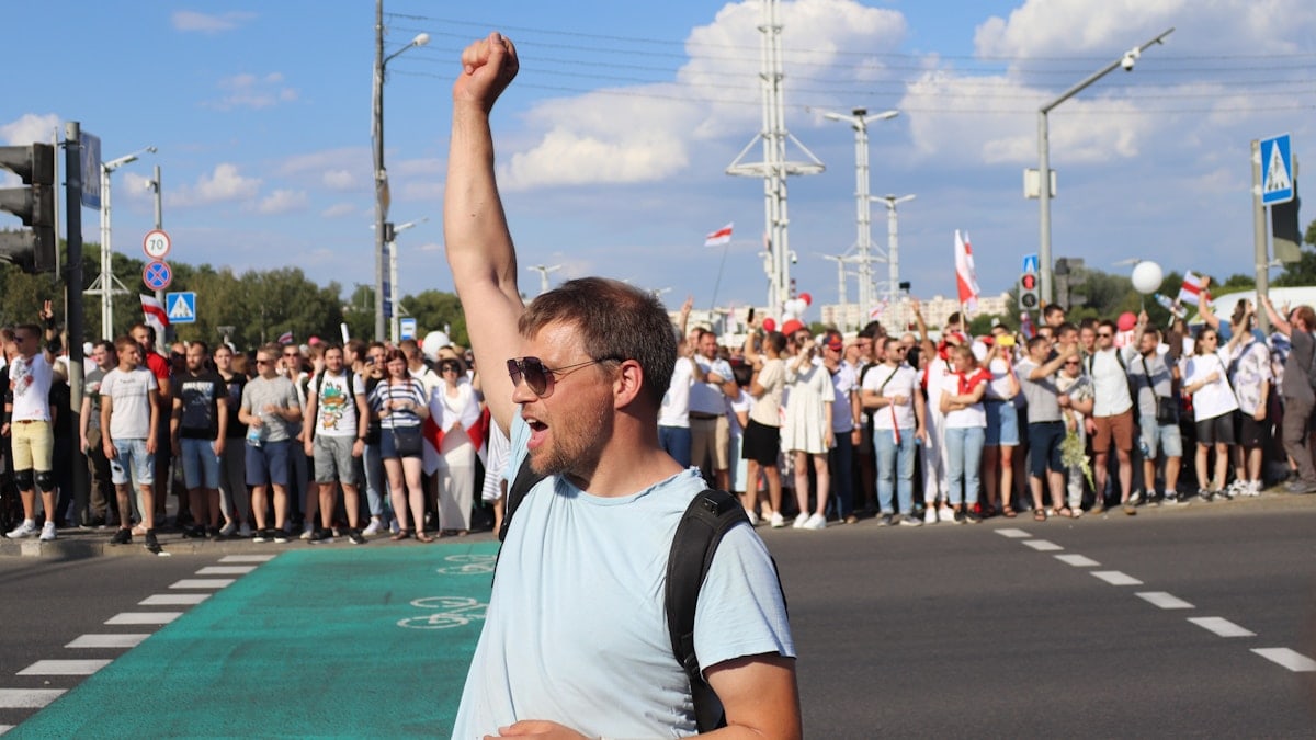 man in white and black crew neck t-shirt raising his right hand